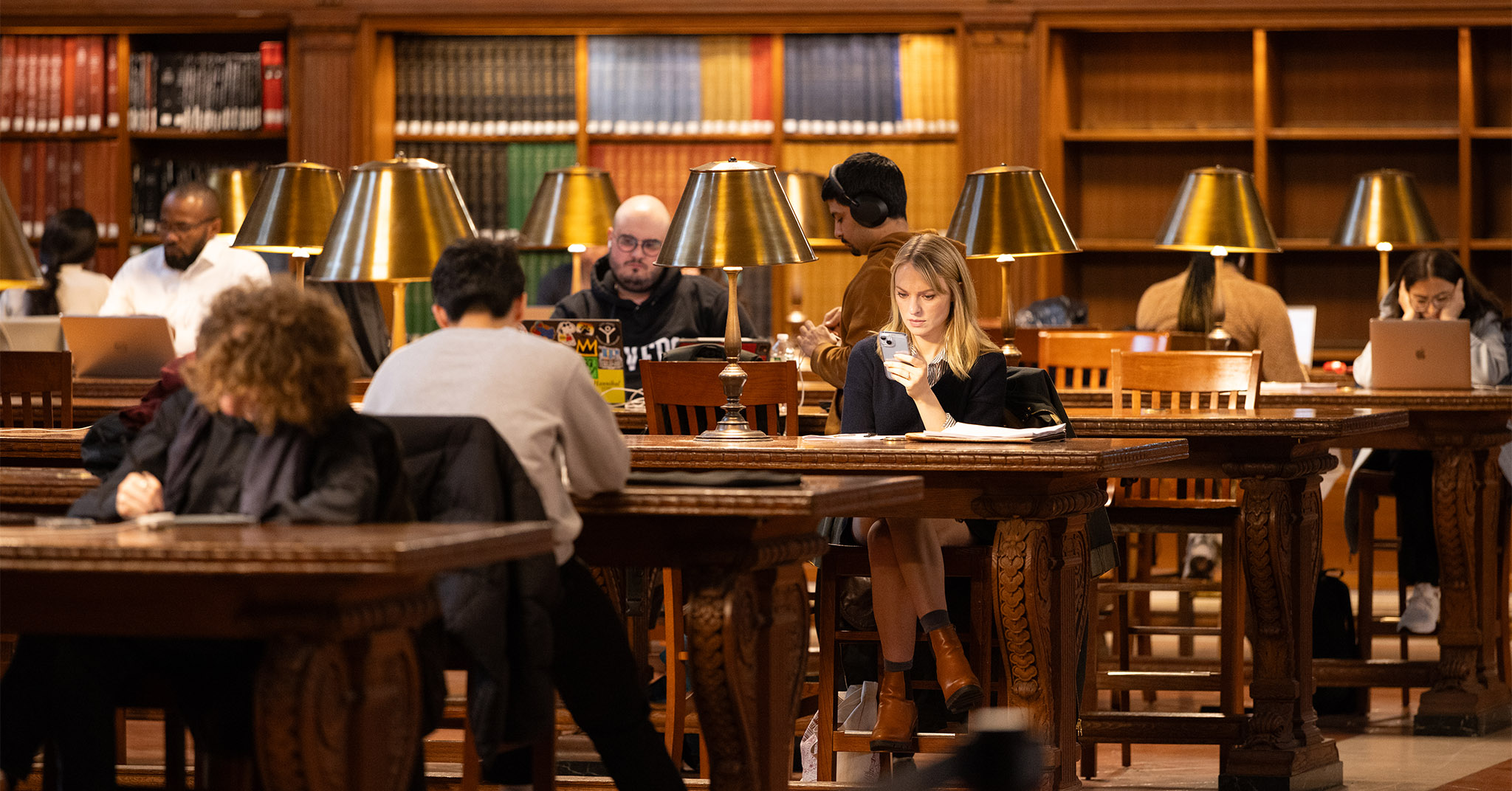 Several people sitting in a library's research room.